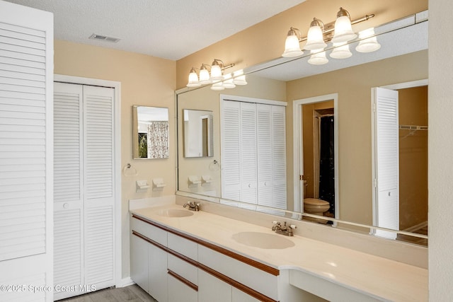 bathroom featuring a closet, visible vents, a sink, and double vanity