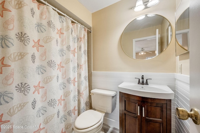 bathroom featuring a shower with shower curtain, wainscoting, vanity, and toilet