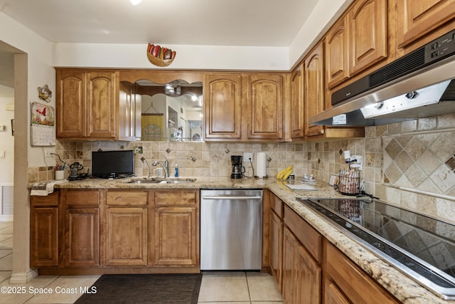 kitchen with stainless steel dishwasher, a sink, light stone countertops, under cabinet range hood, and black electric cooktop