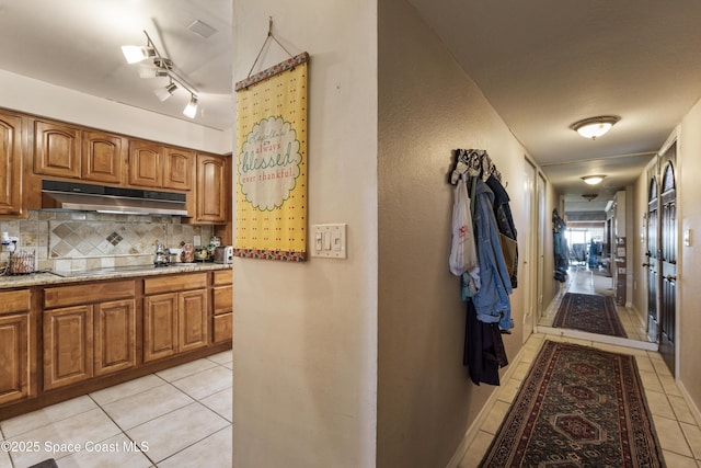 interior space with light tile patterned floors, black electric stovetop, brown cabinetry, and under cabinet range hood