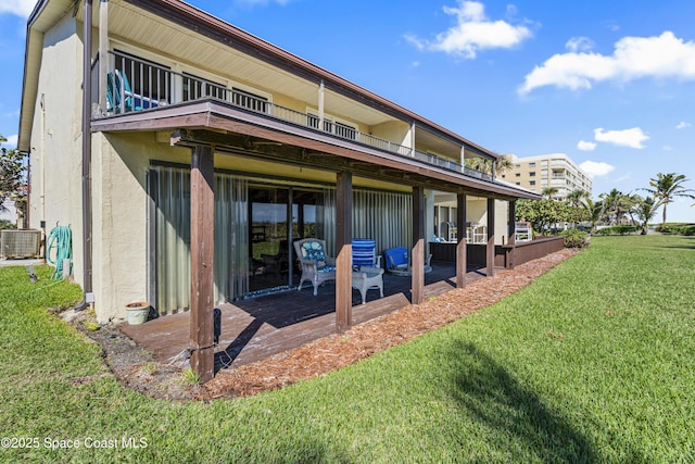 rear view of house featuring a balcony, cooling unit, a yard, a patio area, and stucco siding