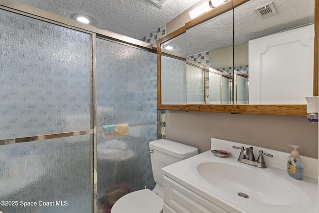 full bathroom with a textured ceiling, toilet, vanity, visible vents, and a shower stall