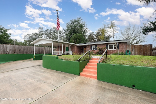 single story home featuring driveway, brick siding, a front lawn, and fence