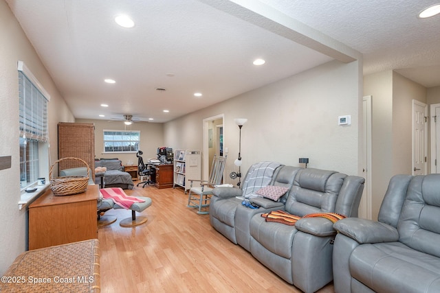 living area featuring a ceiling fan, recessed lighting, light wood-style flooring, and a textured ceiling