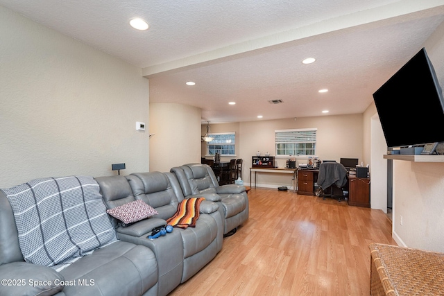 living room with a textured ceiling, light wood-type flooring, baseboards, and recessed lighting