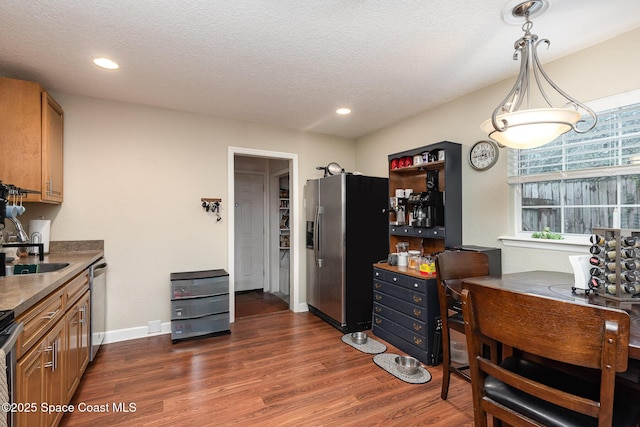 kitchen featuring stainless steel appliances, dark wood-style flooring, a sink, and brown cabinetry