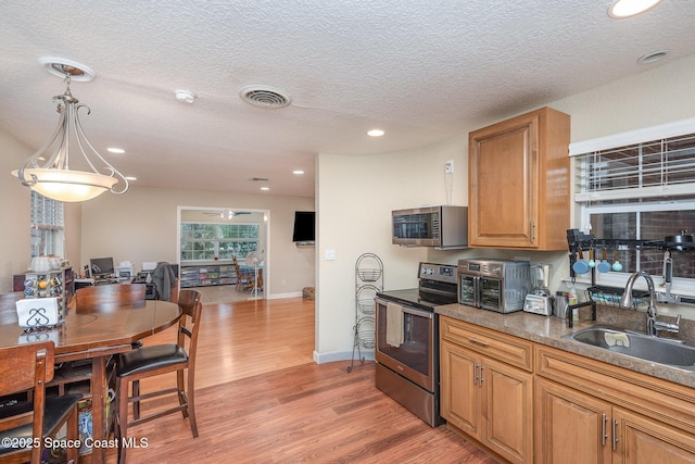 kitchen featuring a sink, visible vents, baseboards, appliances with stainless steel finishes, and light wood-type flooring