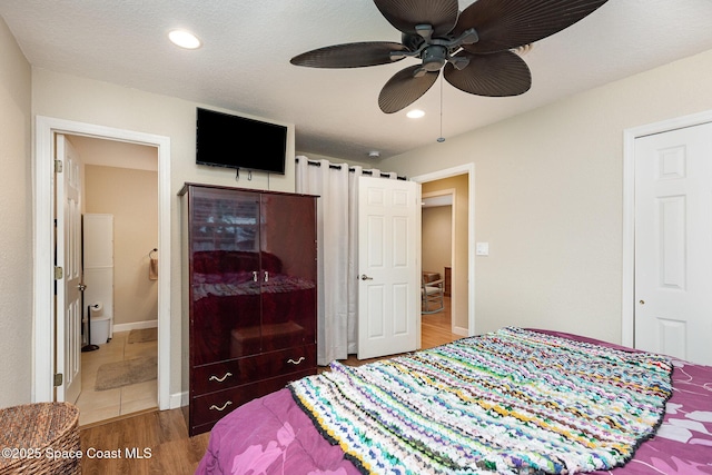 bedroom with ensuite bath, baseboards, wood finished floors, and recessed lighting