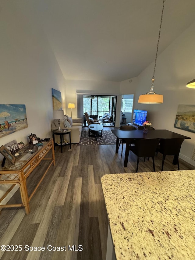 dining room with high vaulted ceiling and dark wood-type flooring