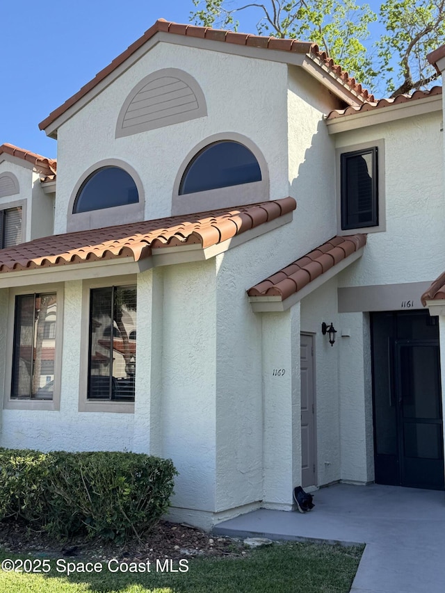 exterior space featuring a tiled roof and stucco siding