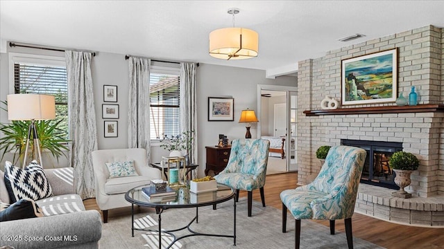 3794 Rambling Acres Dr, Titusville, FL 32796 - living area with a brick fireplace, visible vents, a textured ceiling, and wood finished floors