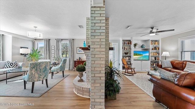 3794 Rambling Acres Dr, Titusville, FL 32796 - living area featuring a textured ceiling, ceiling fan, light wood-style flooring, visible vents, and ornate columns