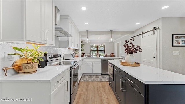 3794 Rambling Acres Dr, Titusville, FL 32796 - kitchen featuring stainless steel appliances, a barn door, white cabinets, wall chimney range hood, and a peninsula