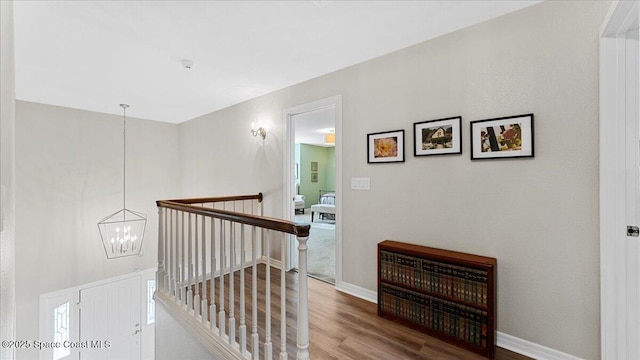 3794 Rambling Acres Dr, Titusville, FL 32796 - hallway featuring an inviting chandelier, baseboards, wood finished floors, and an upstairs landing