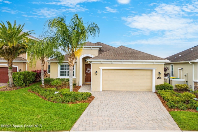 view of front of house with an attached garage, roof with shingles, decorative driveway, stucco siding, and a front lawn