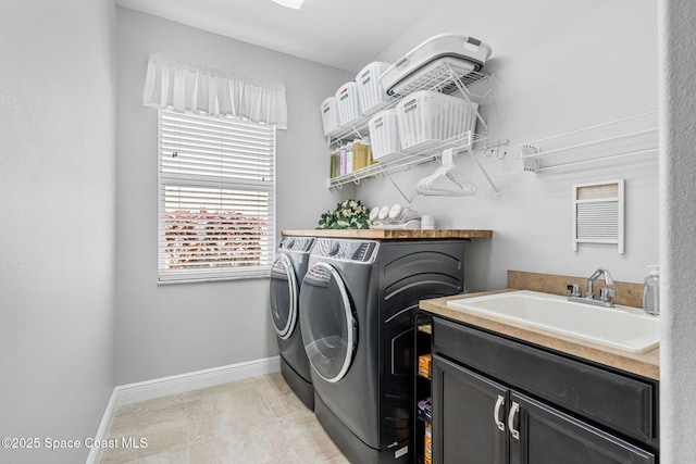 washroom featuring cabinet space, light tile patterned floors, baseboards, washing machine and dryer, and a sink