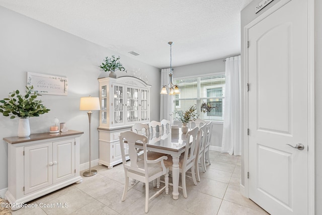 dining area with light tile patterned floors, visible vents, baseboards, a textured ceiling, and a notable chandelier