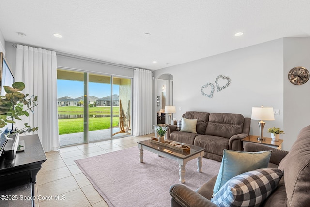 living area featuring arched walkways, light tile patterned flooring, and recessed lighting