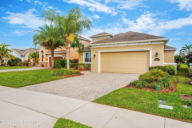 view of front of house with a front lawn, decorative driveway, an attached garage, and stucco siding