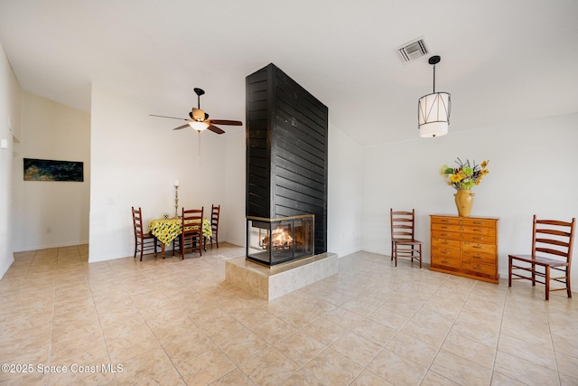 living area with light tile patterned floors, a ceiling fan, visible vents, and a multi sided fireplace