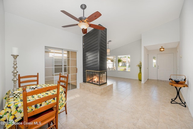 dining room featuring a multi sided fireplace, high vaulted ceiling, a ceiling fan, and light tile patterned flooring