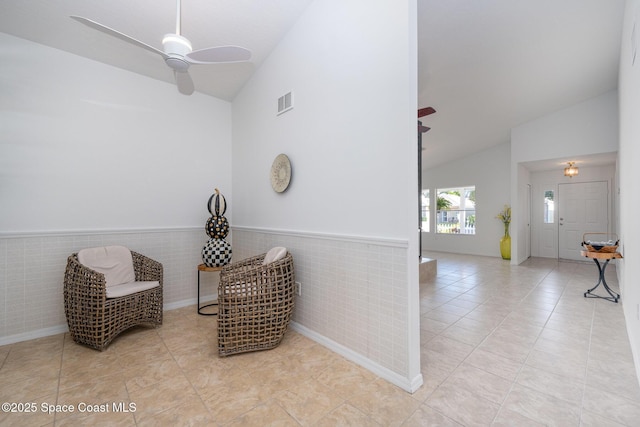 living area with tile patterned flooring, a wainscoted wall, and ceiling fan