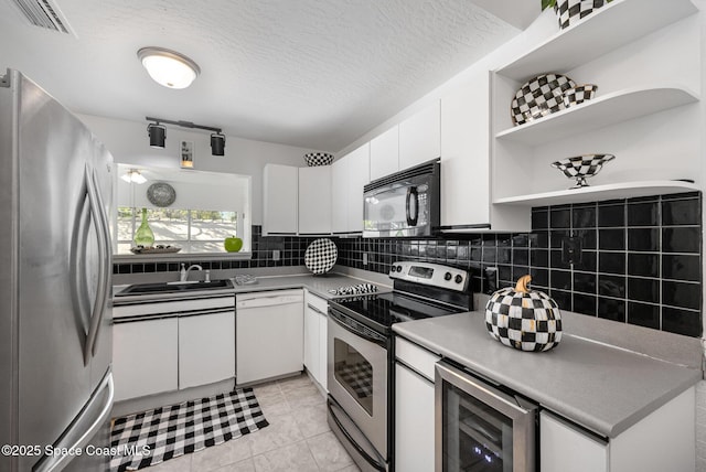 kitchen featuring a sink, backsplash, wine cooler, appliances with stainless steel finishes, and white cabinets