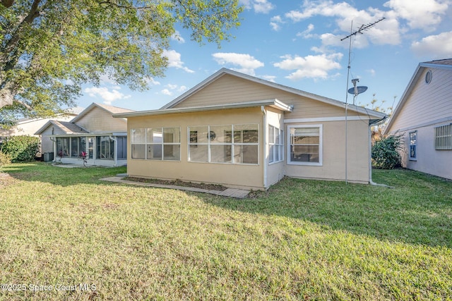 back of property featuring stucco siding, a lawn, and a sunroom