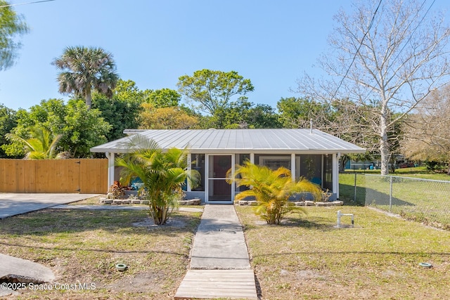 view of front of house with metal roof, fence, and a front lawn