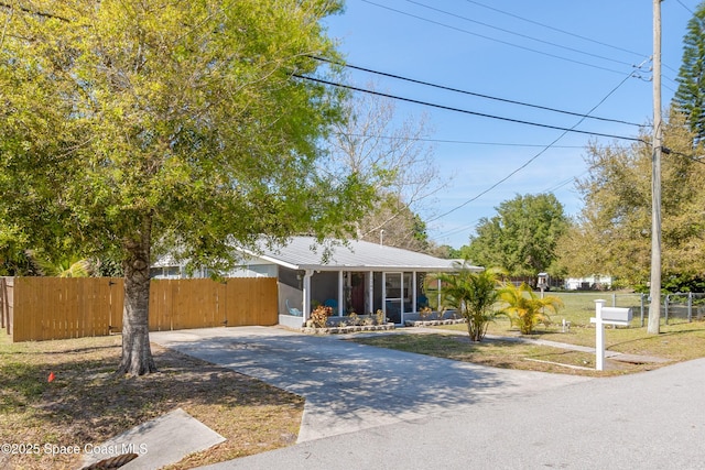 view of front of property featuring metal roof, driveway, a front yard, and fence