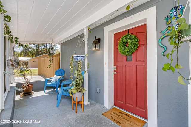 entrance to property featuring a porch and stucco siding