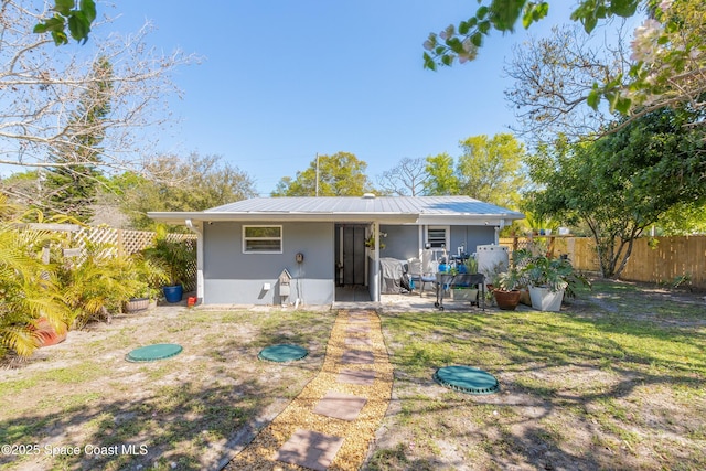 back of property featuring a patio area, fence, metal roof, and a yard