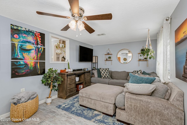 living area featuring ceiling fan, visible vents, and baseboards