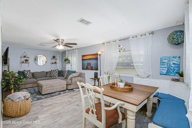 dining space with a ceiling fan, plenty of natural light, visible vents, and wood finished floors