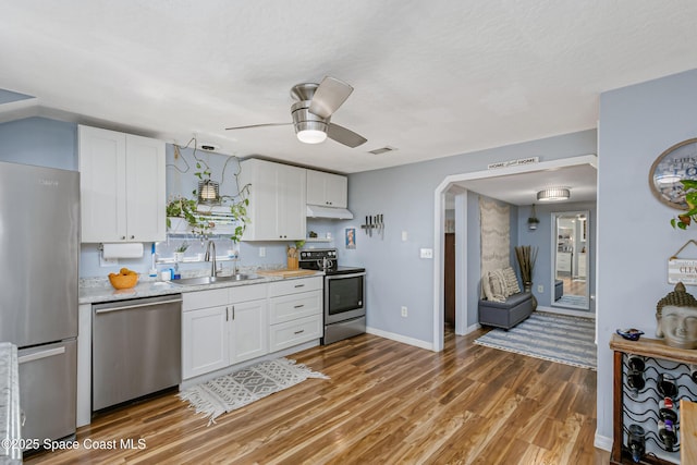 kitchen with stainless steel appliances, light countertops, white cabinets, and a sink