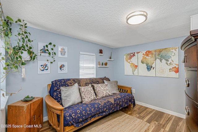 bedroom with a textured ceiling, baseboards, and wood finished floors