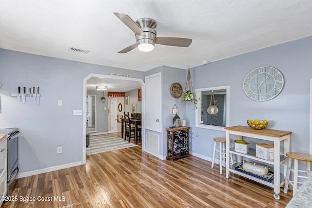 interior space with arched walkways, visible vents, baseboards, and wood finished floors