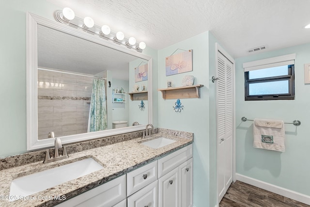 bathroom with visible vents, a sink, a textured ceiling, and baseboards