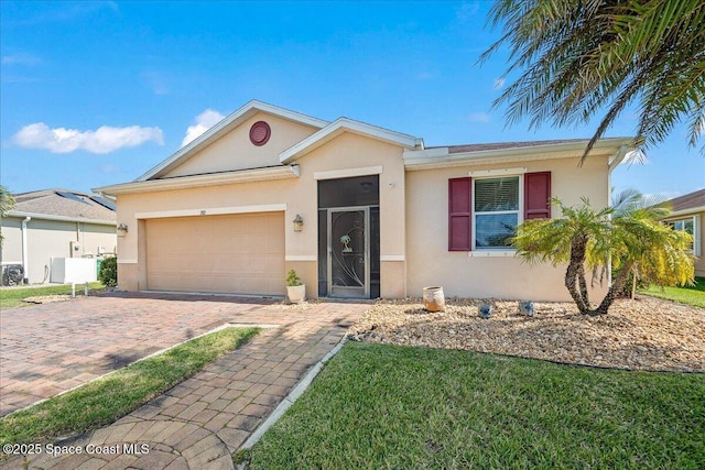 ranch-style home featuring a garage, decorative driveway, and stucco siding