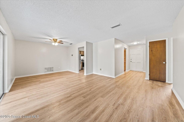 unfurnished living room with light wood-style floors, visible vents, a textured ceiling, and a ceiling fan