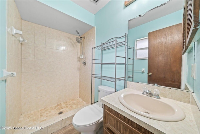 bathroom featuring tiled shower, vanity, and toilet