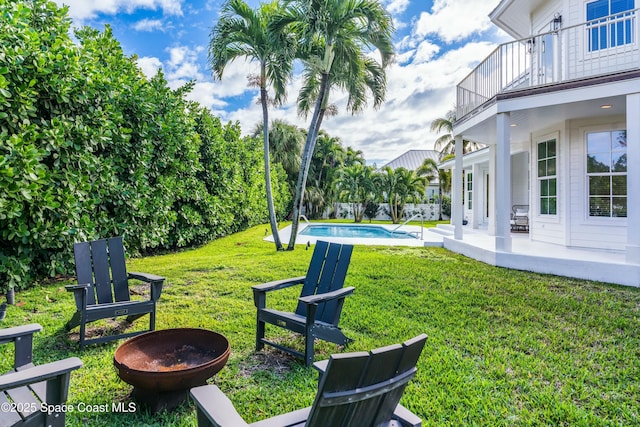 view of yard featuring a fenced in pool, an outdoor fire pit, a patio area, and a balcony