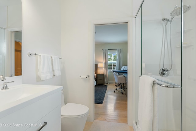 bathroom featuring toilet, connected bathroom, a shower stall, vanity, and wood finished floors