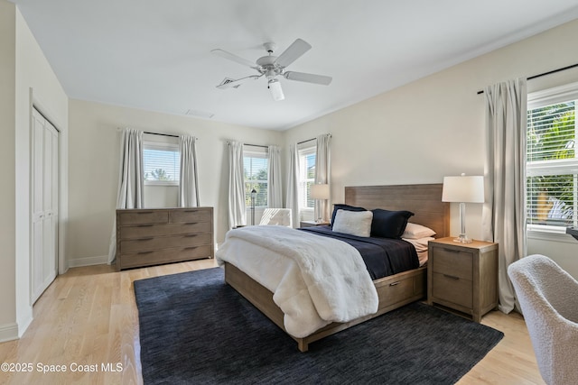 bedroom featuring baseboards, multiple windows, a ceiling fan, and light wood-style floors