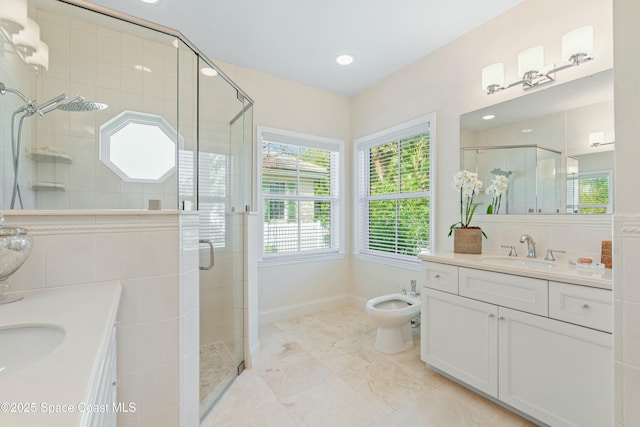 bathroom with a shower stall, a bidet, two vanities, and a sink