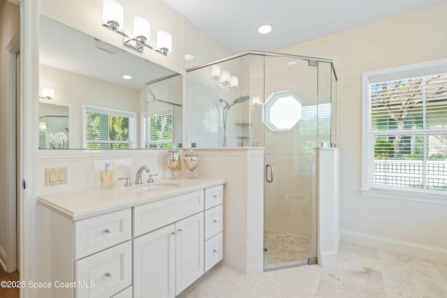 full bathroom featuring a stall shower, plenty of natural light, vanity, and baseboards