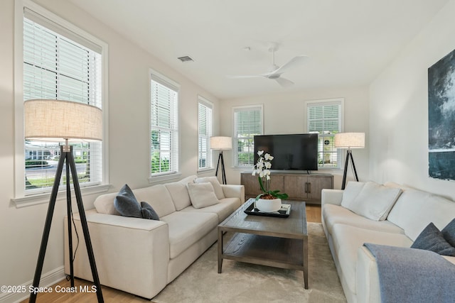 living area with ceiling fan, wood finished floors, visible vents, and baseboards