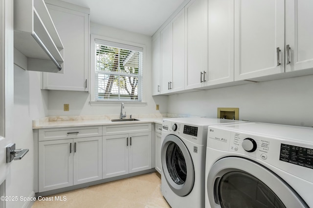 laundry area featuring washer and clothes dryer, a sink, and cabinet space