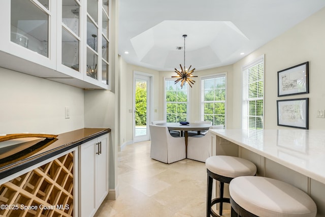 dining room with baseboards, recessed lighting, a raised ceiling, and an inviting chandelier