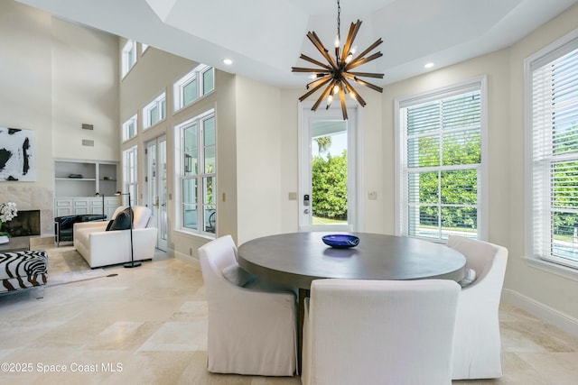 dining room with a chandelier, a high end fireplace, baseboards, and recessed lighting